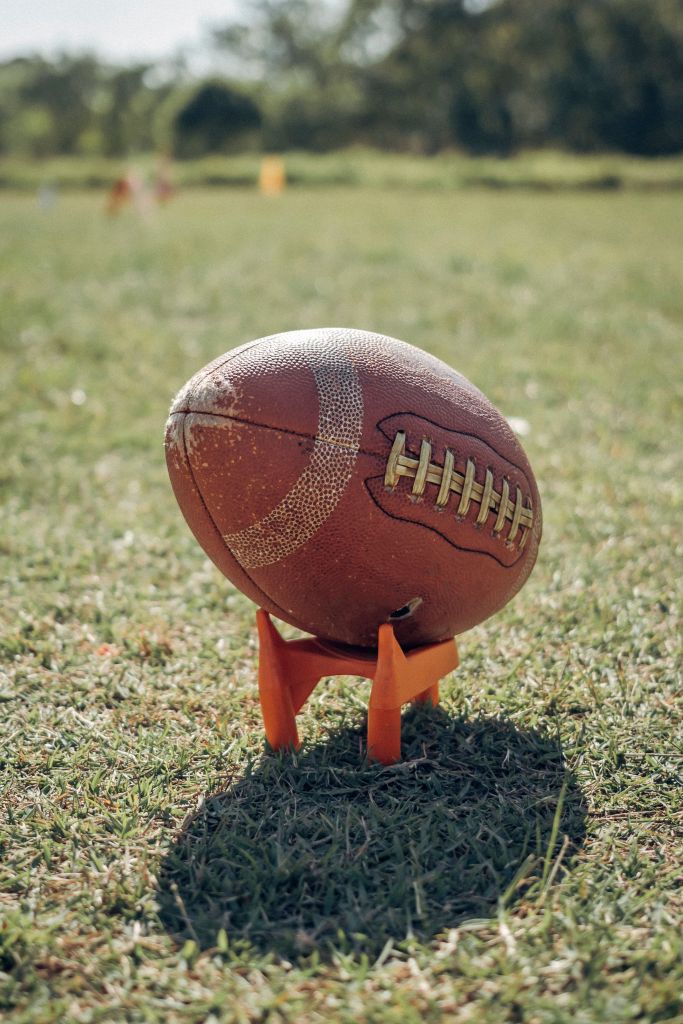 American football resting on a grass field