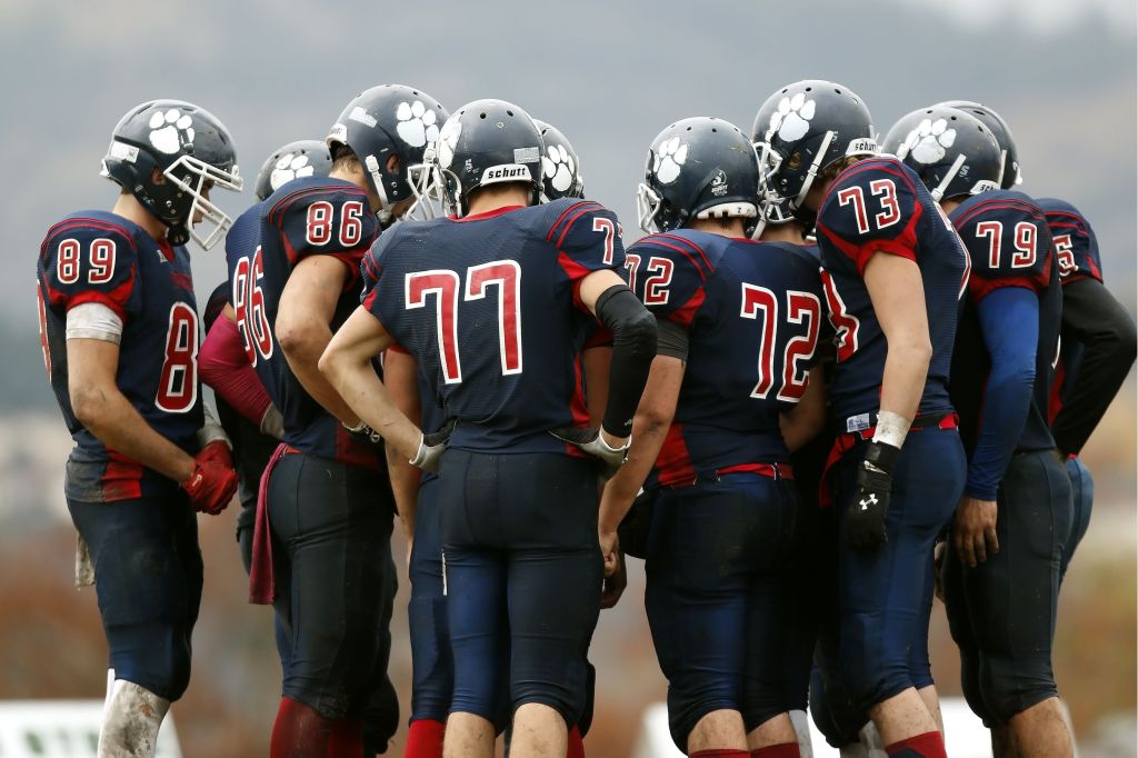 American football players huddle on a grass field