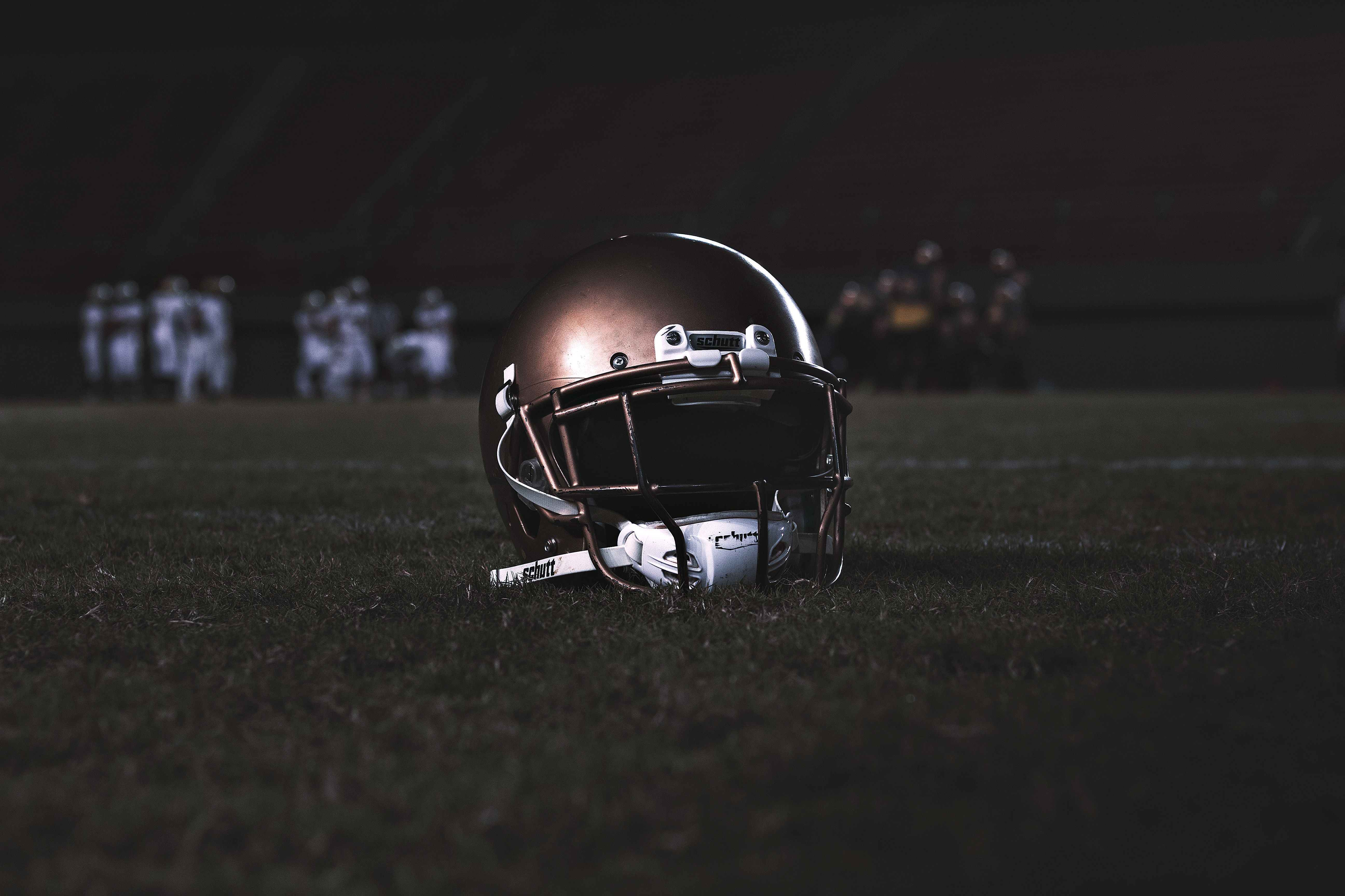 American football helmet resting on grass during a night game