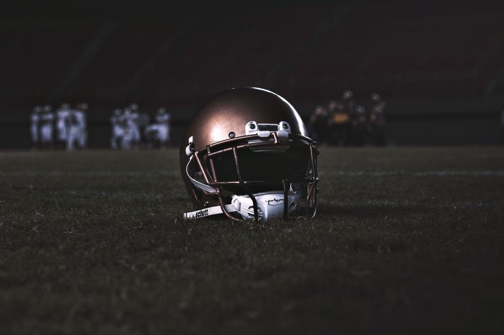 American football helmet resting on grass during a night game