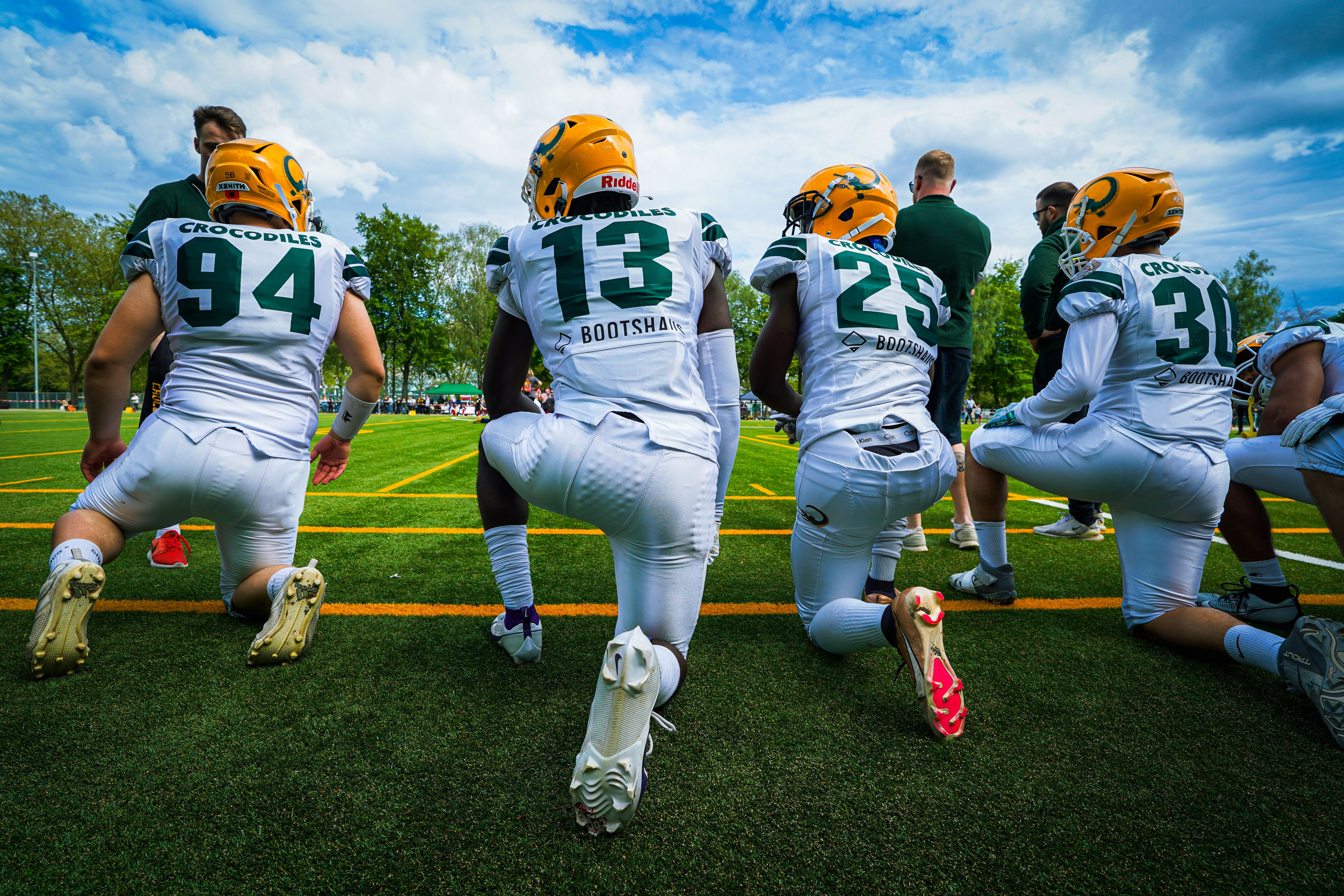 American football players kneeling together in a huddle on a green field
