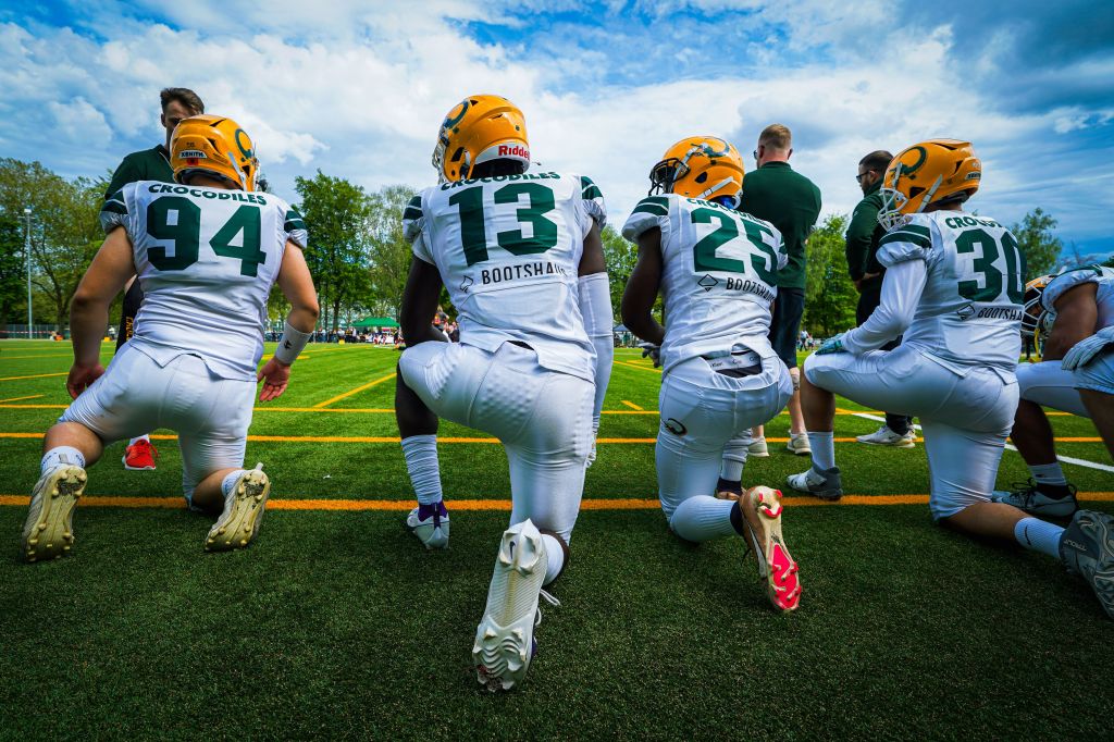 American football players kneeling together in a huddle on a green field